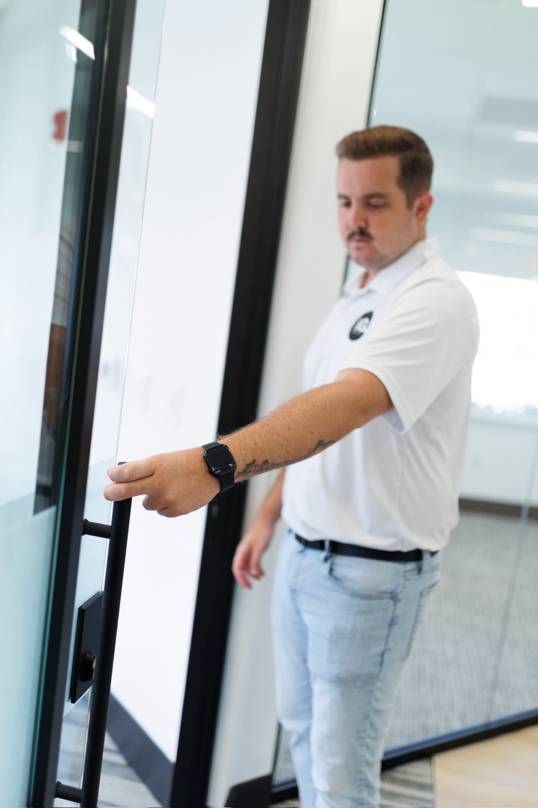 Donovan Laughlin opening a black-framed glass door in a finished commercial suite