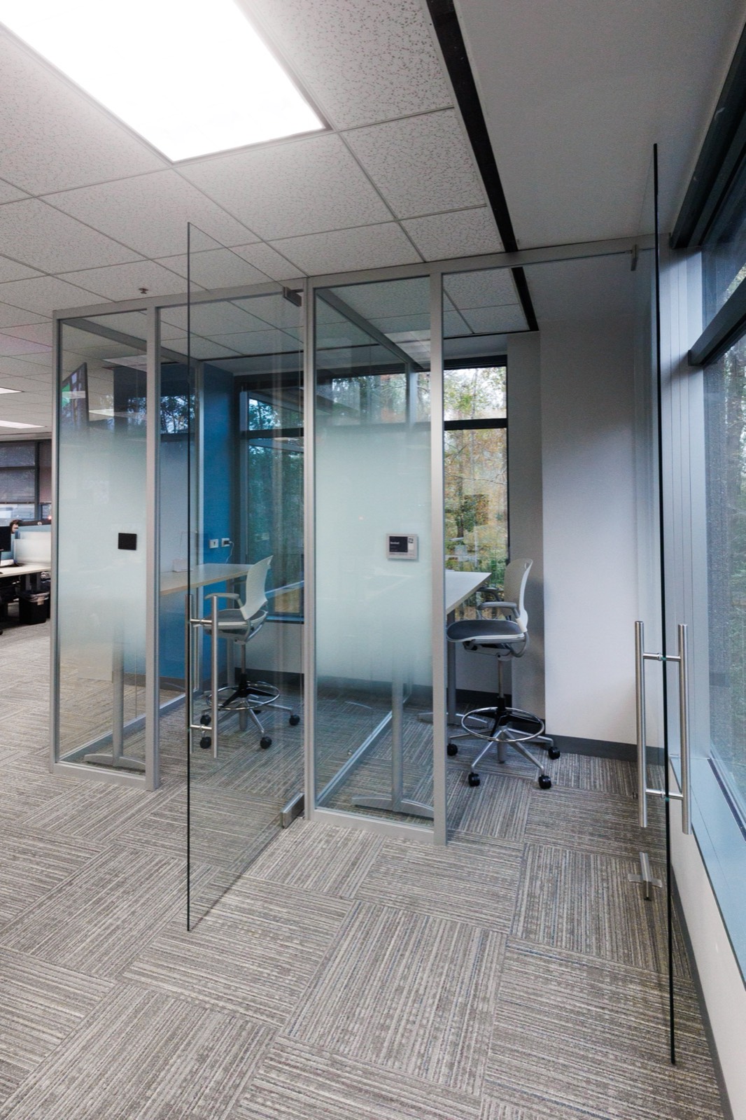 Frameless glass office pods with blue interior — NLP Logix