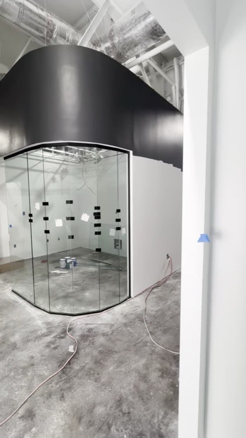 Curved glass wall taking shape under a black soffit