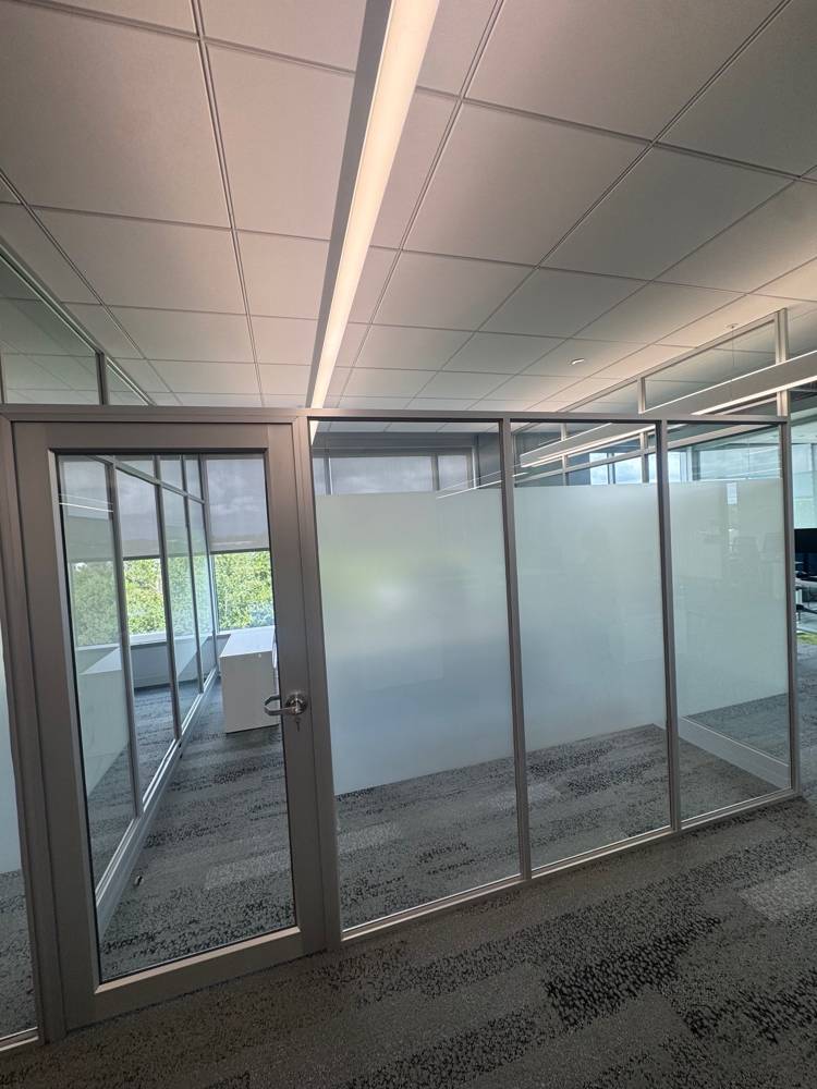 Corner office with a silver-framed glass door and frosted privacy glass front — Duo’s Technologies