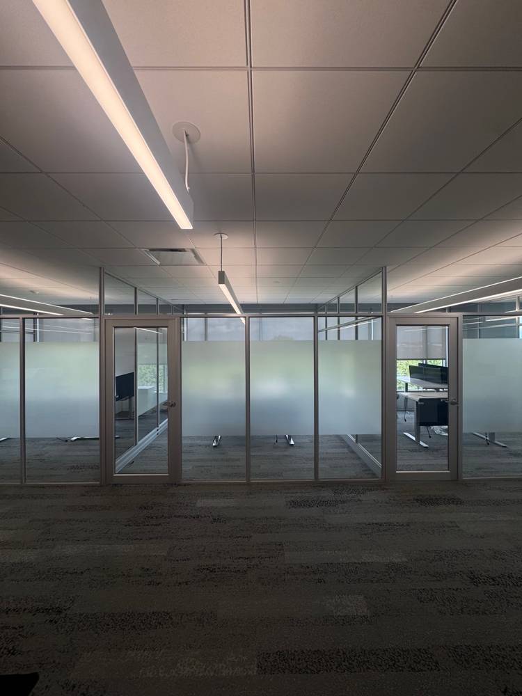 Straight-on view of a row of silver-framed glass offices with frosted bands and framed doors — Duo’s Technologies
