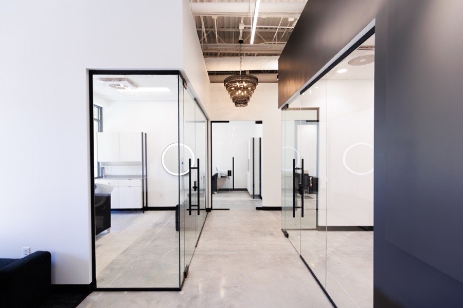 Black-framed glass suite corridor with circular door handles