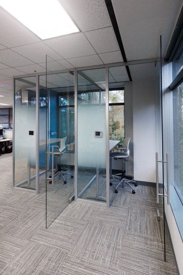 Frameless glass office pods with blue interior — NLP Logix