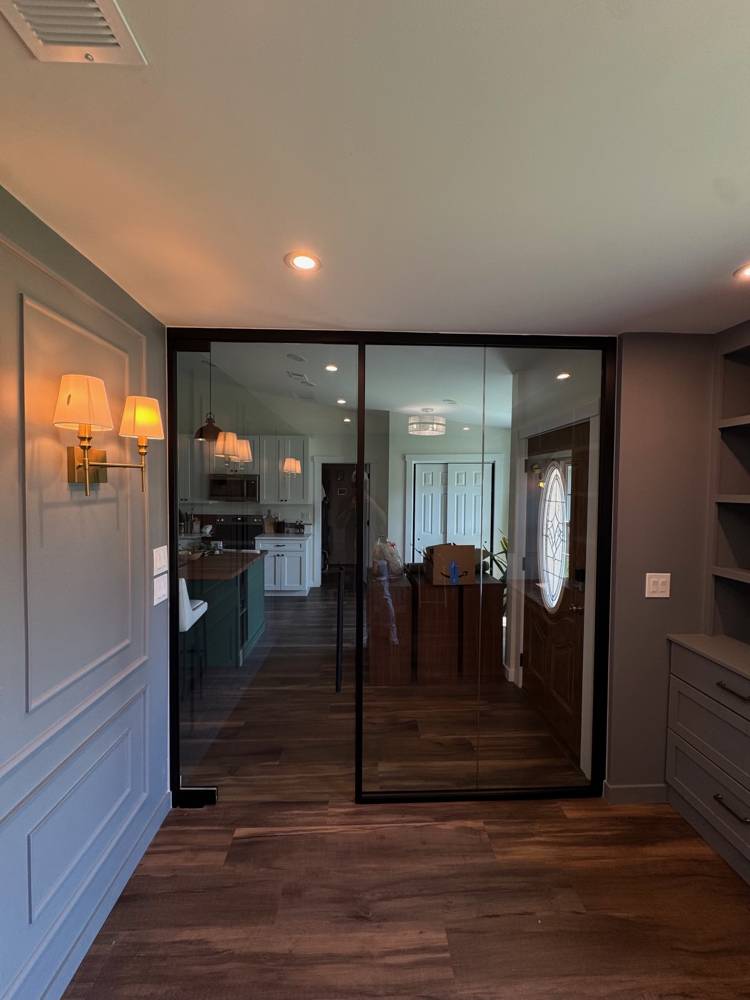 View through the black-framed glass wall from inside the home office toward the kitchen — Residential Office