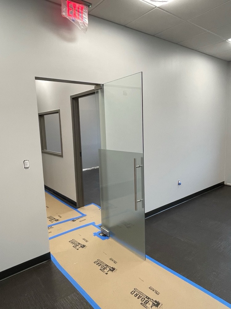 Frameless frosted glass pivot door with silver hardware — Ring Power CAT, Orlando FL
